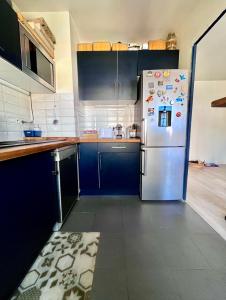 a kitchen with blue cabinets and a refrigerator at Apt central entre stade de France et villette in Aubervilliers +3 photos