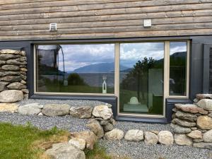 a house with large windows with rocks around it at Leilighet ved fjorden in Årak