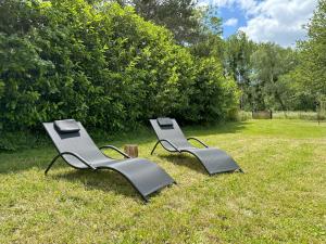 two benches sitting in the grass in a field at Le refuge de Chambord Nature, calme, forêt et prestige des châteaux de la Loire in Thoury +39 photos