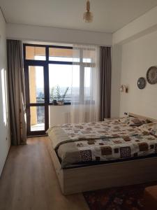 a bedroom with a bed and a large window at Элитная 2х комнатная квартира на набережной c видом на ботаничнеский сад 6мкр in Bishkek