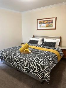 a bed with a black and white comforter in a bedroom at Perth city BNB l CBD and Pool view - 1xKing bed and 2xSingle beds in Perth