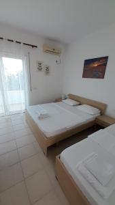 two beds in a white room with a window at Elite 2 Kosta in Dhërmi