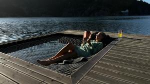 a woman laying on a dock reading a book at Moderne hytte i vannkanten med tilgang til brygge og båt in Risør