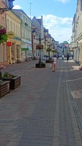 Una mujer caminando por una calle en un pueblo en Drzewna Apartamenty-Kupiecka 40, en Zielona Góra