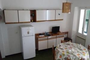 a kitchen with a table and a white refrigerator at Cà du Brenta Casa nel cuore della Liguria in Chiusavecchia