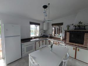 a kitchen with a white table and a white refrigerator at Casita tranquila, con finca y cerca de las playas in Muxia