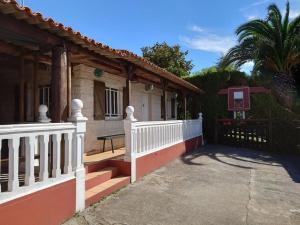 a house with a white fence and a porch at Casita tranquila, con finca y cerca de las playas in Muxia