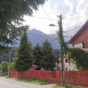 a red fence in front of a house with a mountain at Pensiunea Fara Nume in Buşteni