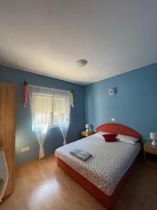 a blue bedroom with a bed and a window at Apartments Simic in Kamenari
