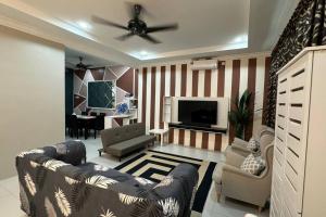 a living room with a couch and chairs and a television at Homestay Bagan Serai in Bagan Serai
