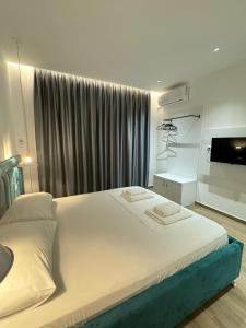 クサミルにあるAjlina Apartmentsの大きな白いベッドとテレビのある寝室