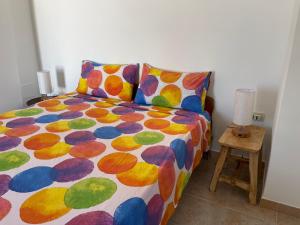 a bed with a colorful comforter and a side table at La Corte di Zia Lucia - vicino Ospedale Panico - Cammino del Salento in Tricase