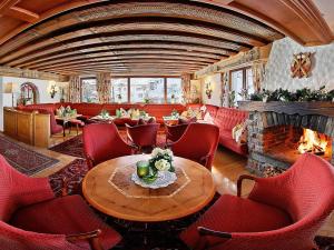 a living room with a fireplace and a table and chairs at Hotel Ulli in Zürs am Arlberg