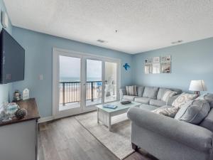 a living room with a couch and a television and a balcony at Love & Memories in North Topsail Beach