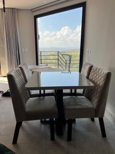 a table and chairs in a room with a large window at Lux Lodge in Jaboticatubas