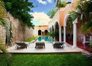 a house with a swimming pool with four benches at Hotel Hacienda Mérida VIP in Mérida
