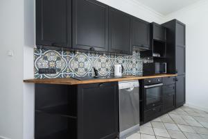 a kitchen with black cabinets and a counter top at Two Bedroom Apartment- Brzozowa - Kazimierz in Kraków