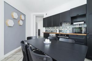 a kitchen with black cabinets and a black table and chairs at Two Bedroom Apartment- Brzozowa - Kazimierz in Kraków