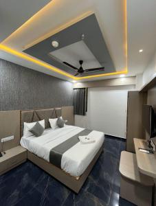 a bedroom with a bed and a desk and a tv at Hotel SERENE STAY in Surat