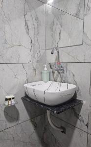 a bathroom with a white sink on a marble wall at Hotel SERENE STAY in Surat
