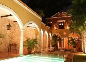 une maison avec une piscine en face d'un bâtiment dans l'établissement Hotel Hacienda Mérida VIP, à Mérida
