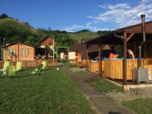 a yard with a cabin with a fence and chairs at Domeniul Paradisului Relax&Fun in Şmig