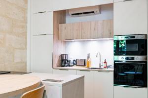 ボルドーにあるMagnifique Appartement Climatise - Proche Garonneの白いキャビネットと黒の電化製品が備わるキッチン