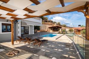 an outdoor patio with chairs and a swimming pool at Evelyn Villa Crete in Tsoutsouros