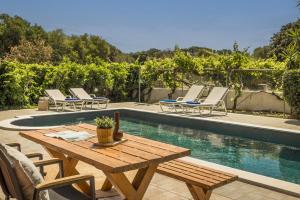 a wooden table and chairs next to a swimming pool at Villa Siora Rosa in Skala Kefalonias