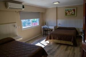 a hotel room with two beds and a desk and a window at Hotel Posadas in Posadas