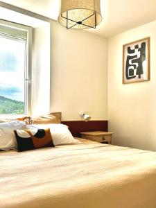 a bedroom with a large bed and a window at Le petit coin charmant in Mercuer