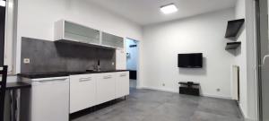 a kitchen with white cabinets and a tv on the wall at Atlas Arena Apartament in Łódź