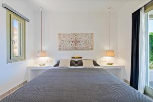 a bed in a white room with two lamps at Lagadia Village in Antiparos