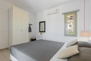 a white bedroom with a bed and a window at Lagadia Village in Antiparos