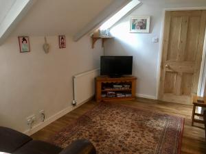 uma sala de estar com uma televisão de ecrã plano e uma porta em Culloden Farmhouse em Camelford