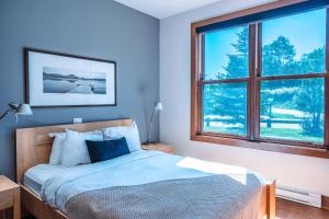 a bedroom with a bed and a large window at Waterfront condo with magnificent view in Lac-Superieur