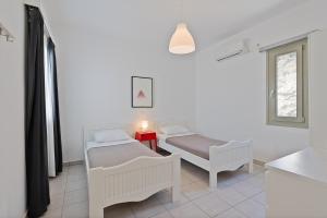 a room with two beds and a table and a window at Lagadia Village in Antiparos