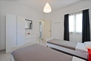 a white bedroom with a bed and a window at Lagadia Village in Antiparos