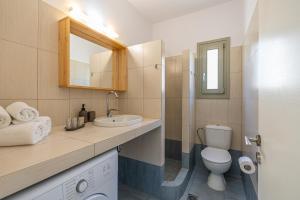 a bathroom with a sink and a toilet and a mirror at Lagadia Village in Antiparos