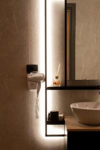 a bathroom with a sink and a hair dryer on the wall at Da Luz Boutique Hotel in Sarandë