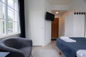 a bedroom with a bed and a chair and a television at City Premium huone Vanha Postitalo in Varkaus