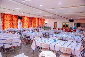 a banquet hall with white tables and chairs at Hôtel Printemps Katana in Kouto +39 photos