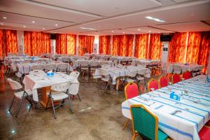a banquet hall with tables and chairs with white tables and red curtains at Hôtel Printemps Katana in Kouto