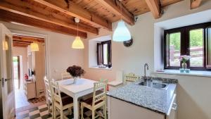 een keuken met een spoelbak en een tafel met stoelen bij Casa vacacional La Coruxa in Vidiago