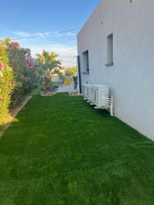 a yard with green grass next to a white building at Villa KAÏS in Lecci