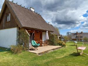 a house with a wooden deck with a table and a chair at Domki przy lesie in Werblinia