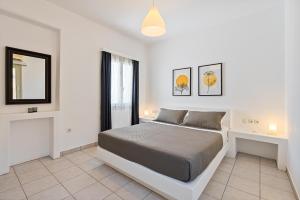 a white bedroom with a bed and a window at Lagadia Village in Antiparos