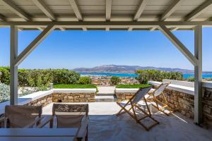 a patio with chairs and a table and a view of the ocean at Lagadia Village in Antiparos