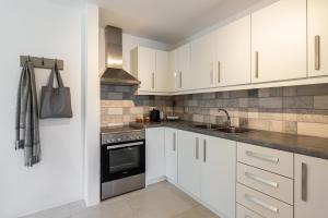 a kitchen with white cabinets and a sink at Lagadia Village in Antiparos