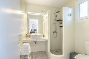 a white bathroom with a sink and a mirror at Lagadia Village in Antiparos